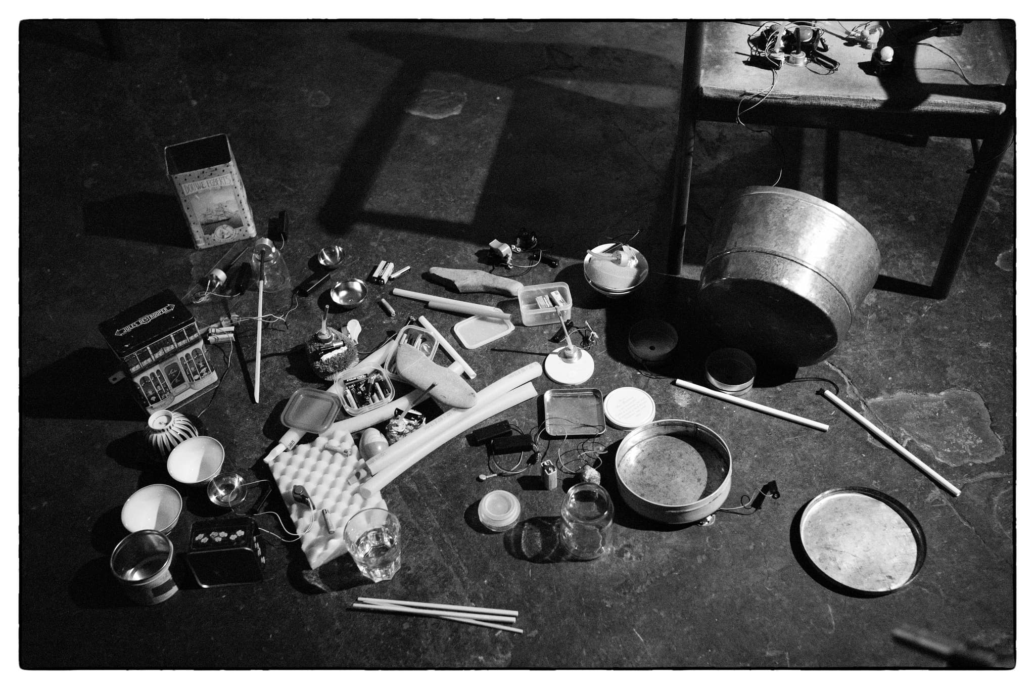 Various kitchen and household items are scattered on a floor, including containers, utensils, and a metal bucket.